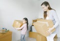 Happy young Asian Mother and her daughter child girl with cardboard boxes in new house at moving day. New rea estate dwelling, Royalty Free Stock Photo