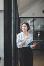 Happy young Asian saleswoman looking out the window welcoming client Royalty Free Stock Photo