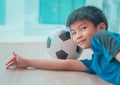 Happy Asian Soccer player kid is sleeping on a football under his head