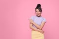 Happy young Asian teen woman standing with her finger pointing isolated on pink background with copy space Royalty Free Stock Photo