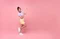 Happy young Asian teen woman standing with her finger pointing isolated on pink background with copy space Royalty Free Stock Photo