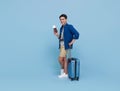 Happy young Asian tourist man holding passport with baggage going to travel on holidays isolated on blue background Royalty Free Stock Photo