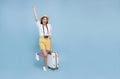 Happy young Asian tourist woman holding baggage going to travel on holidays isolated on blue background Royalty Free Stock Photo