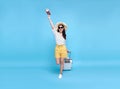 Happy young Asian tourist woman holding passport and boarding pass with baggage going to travel on holidays isolated on blue Royalty Free Stock Photo