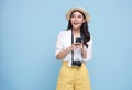 Happy young Asian tourist woman using smartphone application going to travel on holidays isolated on blue background Royalty Free Stock Photo