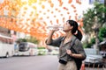 Happy young Asian woman backpack traveler drinking a cold water at China town street food market in Bangkok, Thailand. Traveler Royalty Free Stock Photo