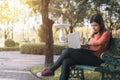 Happy young asian woman be smile working with her laptop on a bench in the park outdoors on vacation time Royalty Free Stock Photo