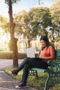 Happy young asian woman be smile working with her laptop on a bench in the park outdoors on vacation time Royalty Free Stock Photo