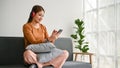 A happy Asian woman wearing headphones, listening to music on a sofa in her living room Royalty Free Stock Photo