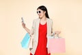 Happy young asian woman celebrating with mobile phone and holding shopping bags isolated on color background Royalty Free Stock Photo