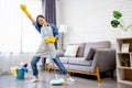 Happy young Asian woman cleaning her home, singing at mop like at microphone and having fun, free space Royalty Free Stock Photo