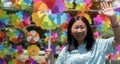 Happy young Asian woman with colorful windmill toy and standing in front of the windmill toy shop Royalty Free Stock Photo