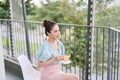 Happy young Asian woman drinking tea at the balcony, relaxing Royalty Free Stock Photo