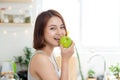 Happy Young Asian Woman Eating Green Apple on Kitchen. Diet. Die Royalty Free Stock Photo