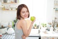 Happy Young Asian Woman Eating Green Apple on Kitchen. Diet. Die Royalty Free Stock Photo