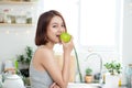 Happy Young Asian Woman Eating Green Apple on Kitchen. Diet. Die Royalty Free Stock Photo