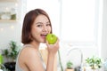 Happy Young Asian Woman Eating Green Apple on Kitchen. Diet. Die Royalty Free Stock Photo