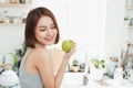 Happy Young Asian Woman Eating Green Apple on Kitchen. Diet. Die Royalty Free Stock Photo