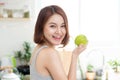Happy Young Asian Woman Eating Green Apple on Kitchen. Diet. Dieting concept. Healthy food Royalty Free Stock Photo
