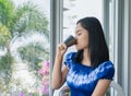 Happy young  Asian woman enjoying and relaxing drinking and looking at a cup of hot coffee drinking coffee the morning Royalty Free Stock Photo