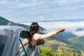 Happy young Asian woman enjoying sitting in a car watching a beautiful mountain view, hand greeting. Driving road trip on vacation Royalty Free Stock Photo