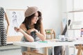 Happy young Asian woman fashion designer or dressmaker, holding tape measure, thinking and looking out of window, working Royalty Free Stock Photo