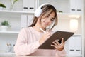 Happy young asian woman with headphones using digital tablet at home Royalty Free Stock Photo