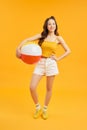 Happy young Asian woman holding beach ball in summer holiday travel on orange background Royalty Free Stock Photo