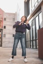 Happy young asian woman listening to music and having fun with headphones via smartphone on the street. Royalty Free Stock Photo