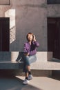 Happy young asian woman listening to music with headphones via smartphone and having fun while sitting side the street. Royalty Free Stock Photo