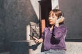 Happy young asian woman listening to music with headphones via smartphone and having fun while sitting side the street. Royalty Free Stock Photo