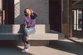 Happy young asian woman listening to music with headphones via smartphone and having fun while sitting side the street. Royalty Free Stock Photo