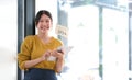 Happy young Asian woman owner standing holding a tablet with open sign board. Royalty Free Stock Photo