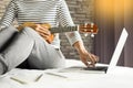 Happy young asian woman playing ukulele sitting on bed in bedroom. Royalty Free Stock Photo