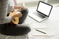 Happy young asian woman playing ukulele sitting on bed in bedroom. Royalty Free Stock Photo