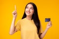 Happy young Asian woman pointing up to copy space and looking at copy space with smile face holding credit card Pretty girl act Royalty Free Stock Photo