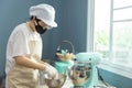 Happy young Asian woman with protective face mask, apron is smiling, baking homemade cake or bakery first time in home kitchen, Royalty Free Stock Photo