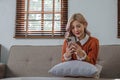 Happy young asian woman relaxing at home. Female is lying down on sofa and using mobile smartphone Royalty Free Stock Photo