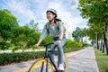 Happy young Asian woman while riding a bicycle in a city park. She smiled using the bicycle of transportation. Environmentally Royalty Free Stock Photo