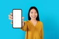 Happy young asian woman showing smartphone with blank screen, mockup Royalty Free Stock Photo