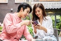 Happy Young asian woman sitting with boyfriend at cafe table, discussing over on smartphone, Young couple looking at mobile phone Royalty Free Stock Photo