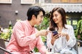 Happy Young asian woman sitting with boyfriend at cafe table, discussing over on smartphone, Young couple looking at mobile phone Royalty Free Stock Photo