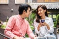 Happy Young asian woman sitting with boyfriend at cafe table, discussing over on smartphone, Young couple looking at mobile phone Royalty Free Stock Photo