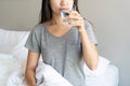 Happy young Asian woman smiling and enjoying fresh clean water while sitting on bed in morning. Diet girl drinking water after Royalty Free Stock Photo