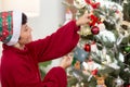 Happy young asian woman smiling hanging decorating ornament on Christmas tree in the living room at home.