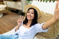 Happy young Asian woman taking selfie while lying in hammock near RV on autumn vacation in countryside Royalty Free Stock Photo