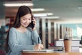 Happy young asian woman talking on mobile phone while sitting in library Royalty Free Stock Photo