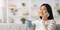 Happy Young Asian Woman Talking On Phone And Drinking Tea At Home Royalty Free Stock Photo