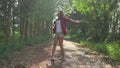 Happy young Asian woman traveler with backpack walking in forest. Hiker Asian woman with backpack walking on path in summer forest