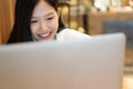 Happy young Asian woman using phone and working with a laptop in the coffee shop cafe office. Royalty Free Stock Photo